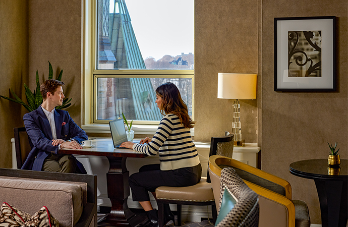A man and woman in Fairmont Le Château Frontenac sitting across a table working on a laptop